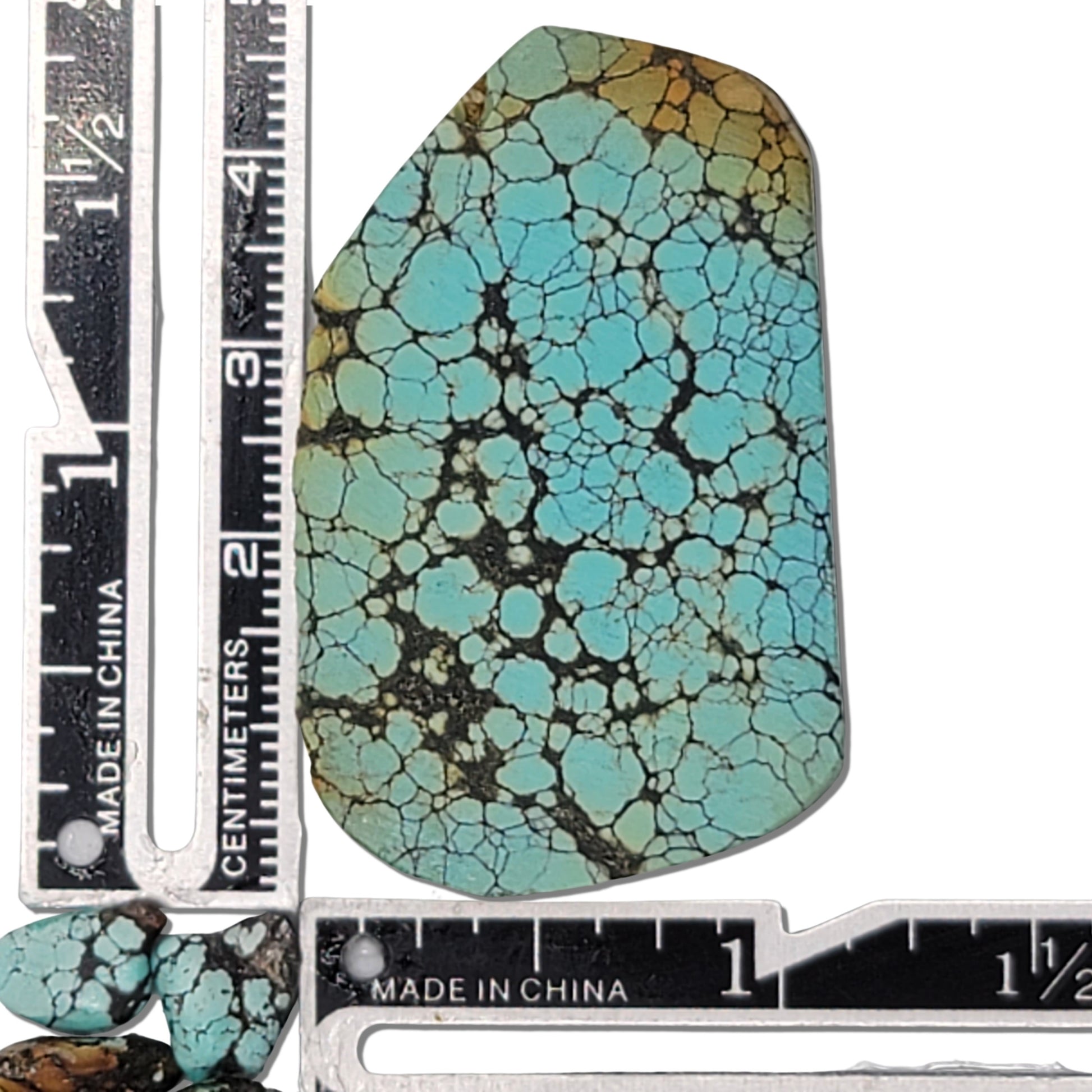 Natural turquoise rough stone with vibrant blue coloring and intricate black web matrix pattern, shown with measuring scale for size reference – premium turquoise for jewelry making at NaturalTurquoise.com.