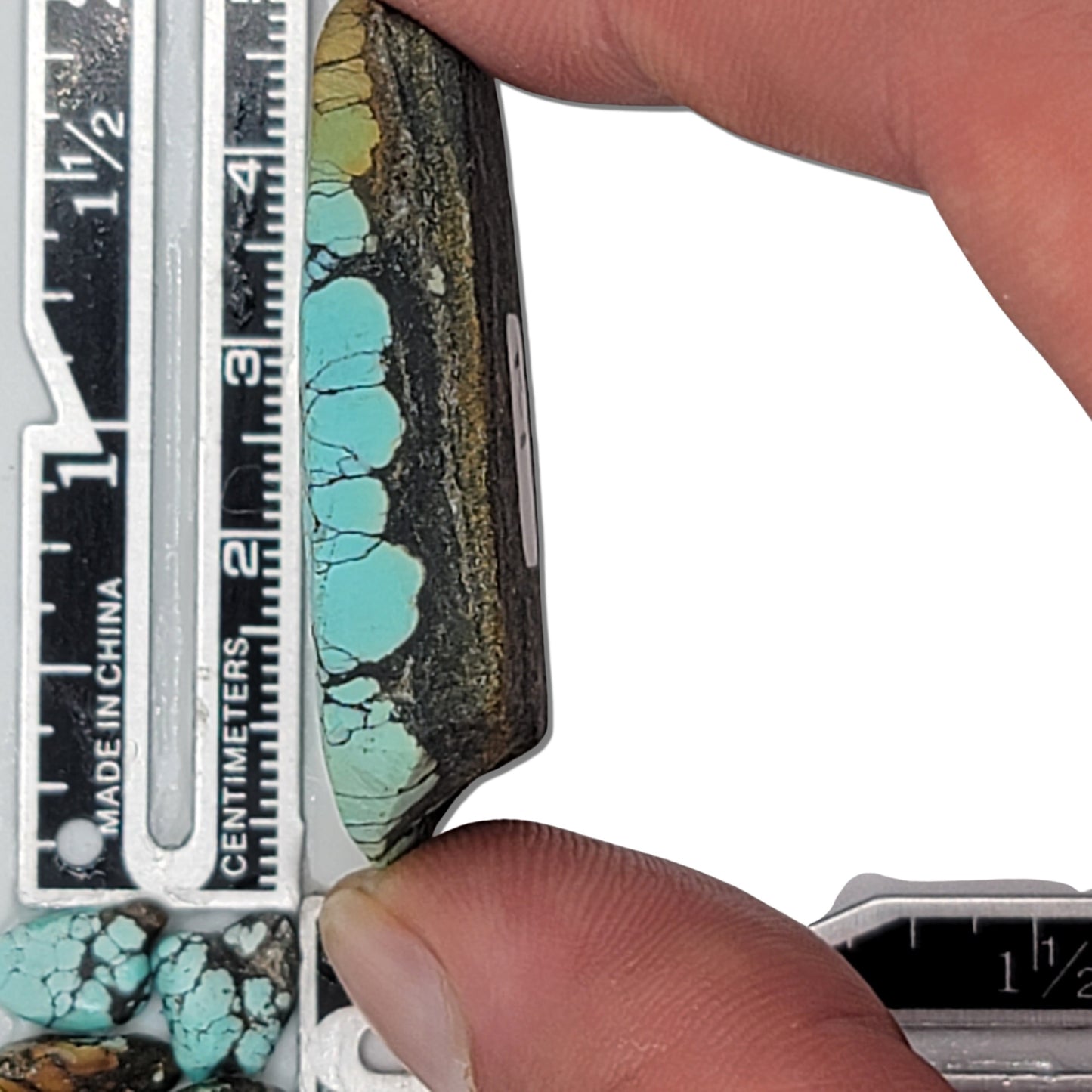 Natural turquoise rough stone with vibrant blue coloring and intricate black web matrix pattern, shown with measuring scale for size reference – premium turquoise for jewelry making at NaturalTurquoise.com.