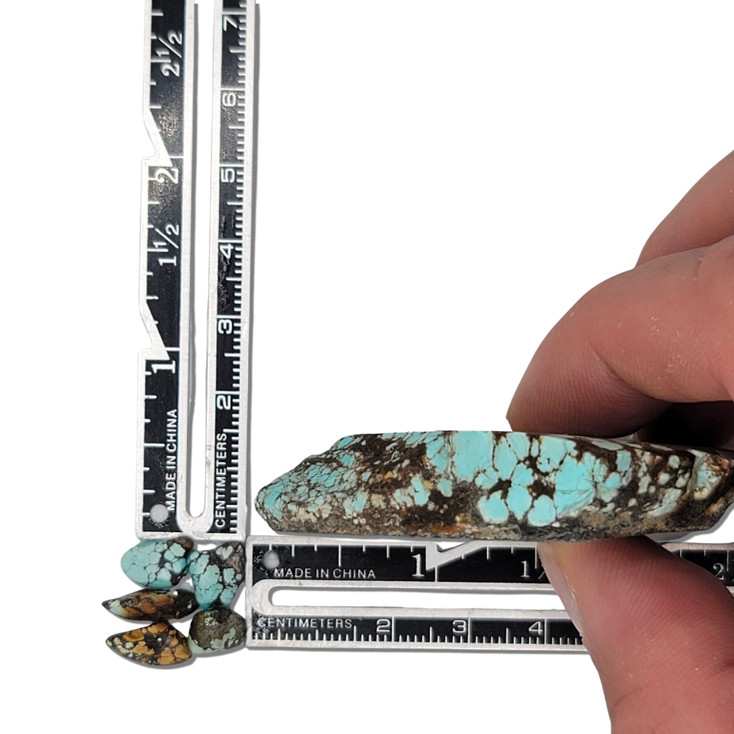 Large natural turquoise rough stone with a bright blue and dark brown matrix pattern, shown with measuring scale and additional smaller turquoise pieces for size reference – premium turquoise for jewelry making at NaturalTurquoise.com.