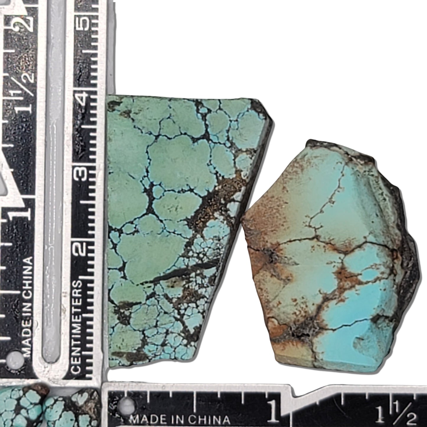 A pair of natural turquoise stones weighing 24 grams, featuring light blue-green hues with dark and golden-brown matrix patterns. The stones measure approximately 4.5 cm x 3 cm and 3.5 cm x 2.5 cm, displayed with a ruler for scale. Available for purchase at www.naturalturquoise.com.