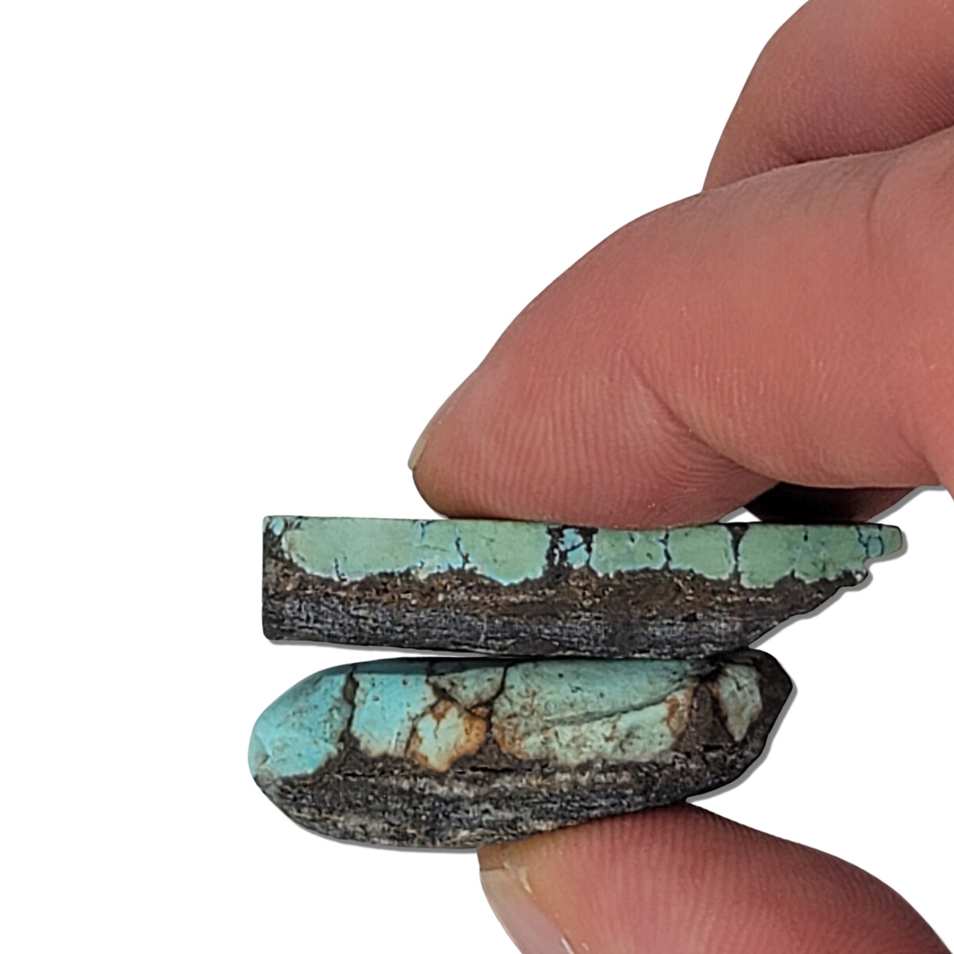 A pair of natural turquoise stones weighing 24 grams, featuring light blue-green hues with dark and golden-brown matrix patterns. The stones measure approximately 4.5 cm x 3 cm and 3.5 cm x 2.5 cm, displayed with a ruler for scale. Available for purchase at www.naturalturquoise.com