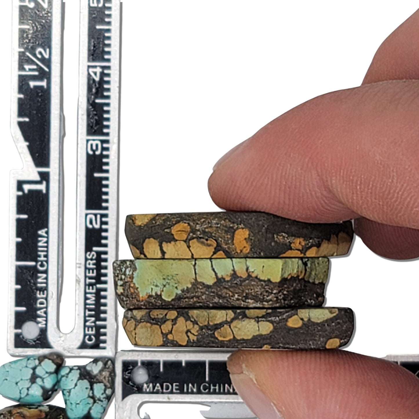 A natural turquoise stone triplet weighing 18 grams, featuring earthy golden and green tones with bold dark matrix patterns. The stones measure approximately 4 cm x 3 cm, 3.8 cm x 2.7 cm, and 3.5 cm x 2.5 cm, displayed with a ruler for scale. Available for purchase at www.naturalturquoise.com, ideal for lapidary and jewelry projects.