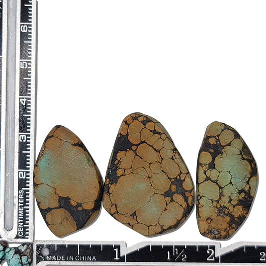 A natural turquoise stone triplet weighing 18 grams, featuring earthy golden tones with green highlights and bold dark matrix patterns. The stones measure approximately 4 cm x 2.5 cm, 3.8 cm x 2.7 cm, and 3.5 cm x 2.5 cm, displayed with a ruler for scale. Available for purchase at www.naturalturquoise.com, ideal for lapidary and jewelry projects.