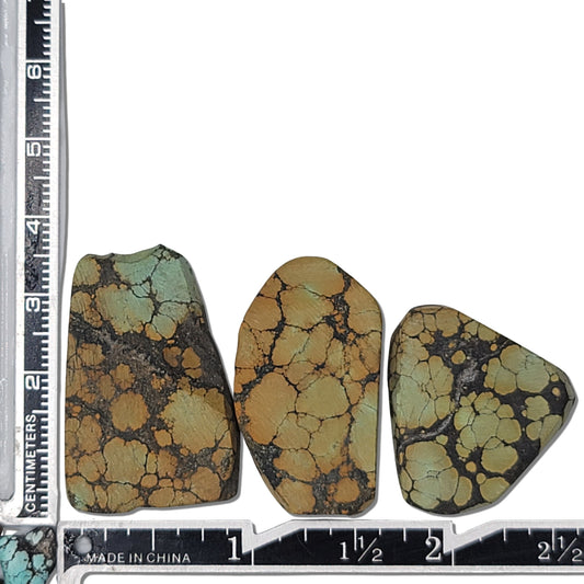 A natural turquoise stone triplet weighing 18 grams, featuring earthy golden tones with green highlights and bold dark matrix patterns. The stones measure approximately 4 cm x 2.8 cm, 3.8 cm x 2.7 cm, and 3.5 cm x 2.5 cm, displayed with a ruler for scale. Available for purchase at www.naturalturquoise.com, ideal for lapidary and jewelry projects