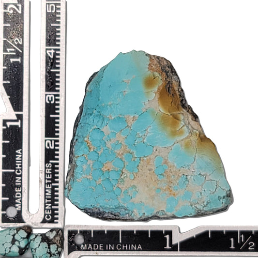 Natural turquoise rough stone with vibrant blue and earthy brown matrix, shown with measuring scale for size reference – high-quality turquoise for sale at NaturalTurquoise.com
