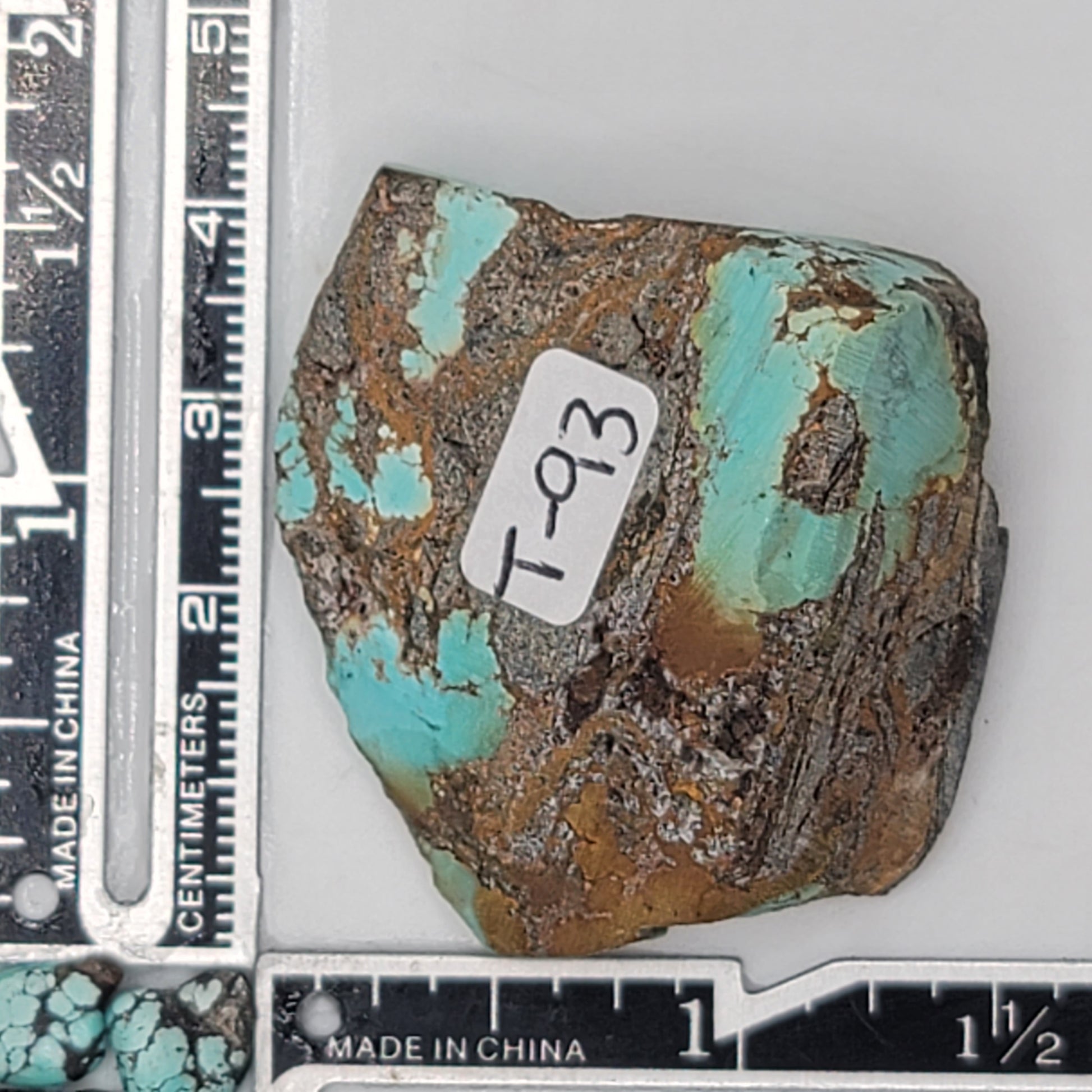 A natural turquoise stone weighing 39 grams, featuring vibrant blue-green tones with warm earthy accents and a bold dark matrix. The stone measures approximately 5.5 cm x 4 cm x 0.8 cm, displayed with a ruler for scale. Available for purchase at www.naturalturquoise.com, perfect for lapidary and jewelry projects.