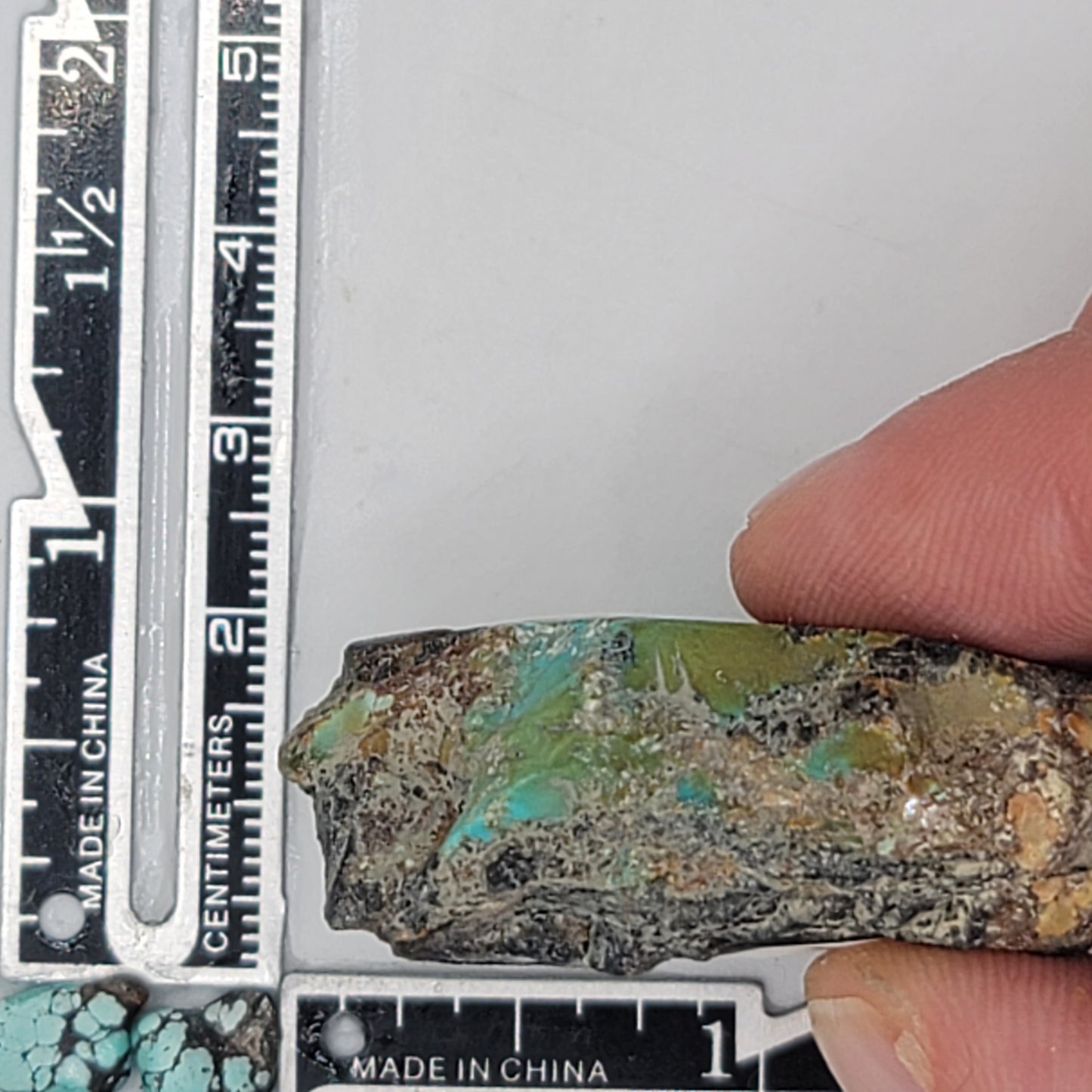 A natural turquoise stone weighing 36 grams, featuring vibrant blue and green hues with earthy tones and bold dark matrix patterns. The stone measures approximately 5 cm x 3.8 cm x 0.7 cm, displayed with a ruler for scale. Available for purchase at www.naturalturquoise.com, perfect for lapidary and jewelry projects.